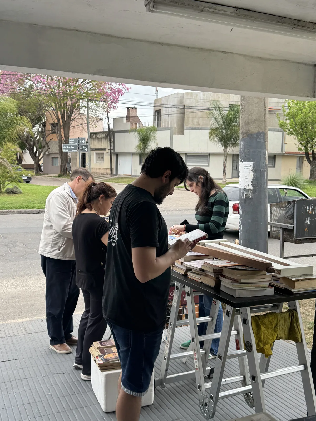 Personas eligiendo libros en la mesa de la vereda